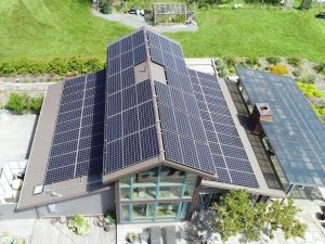 FMS Grid Tie Solar Installation Aerial view of a modern house with extensive solar panels on the roof, viewed from above.